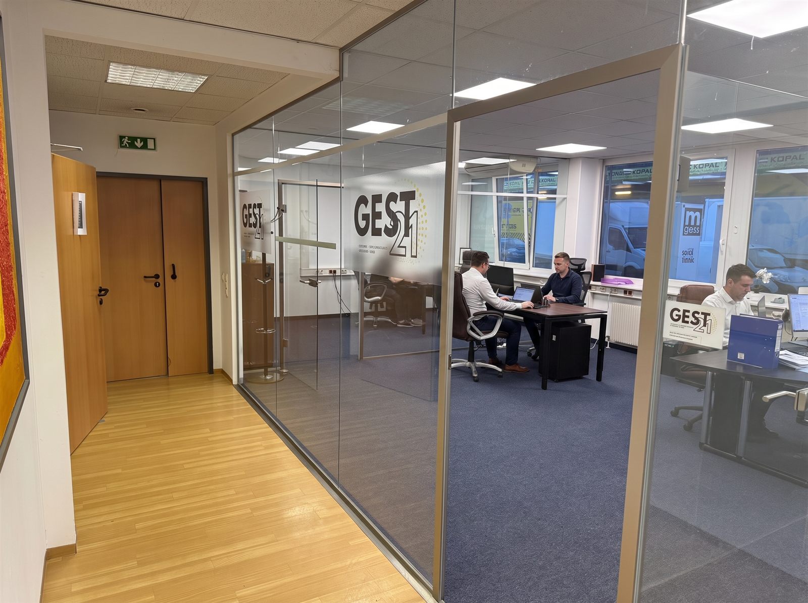 Team-Office mit arbeitendem Team hinter Glasfront